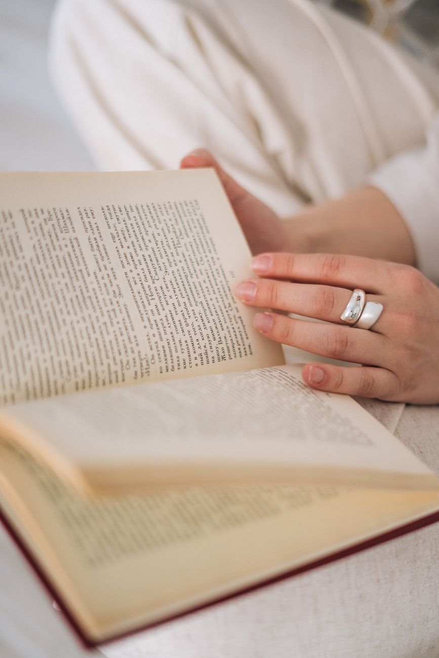 person wearing silver ring holding a book. Photo by Tima Miroshnichenko on Pexels.com