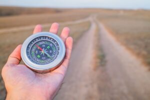 compass held in hand pointing at open pathway